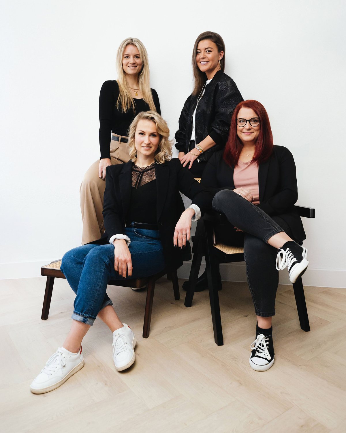 Das Team von Blickkontakt Schauer: vier Optikerinnen sitzend und stehend vor heller Wand